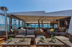 an outdoor living area with couches and tables on the deck overlooking the ocean,