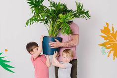 a man holding a potted plant next to two children