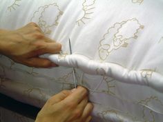 someone is cutting up the edge of a pillow with scissor and thread on it