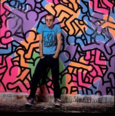 a man standing in front of a colorful wall with graffiti on it's sides