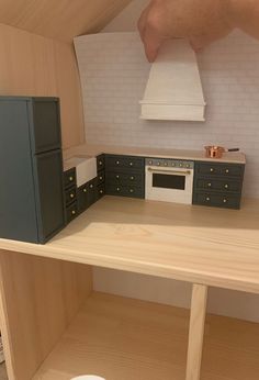 a model kitchen is shown in the shape of a stove and oven, with two hands reaching for it