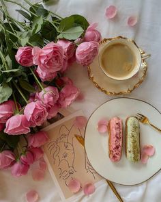 a plate with two pastries on it next to pink flowers and a cup of coffee