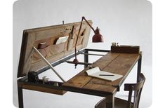 a wooden desk with a lamp on top of it next to a chair and table