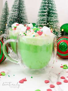 two mugs filled with green hot chocolate and sprinkles on the side