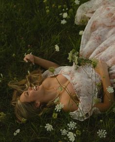 a woman laying in the grass with flowers