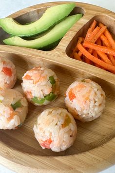 sushi rolls and carrots on a wooden platter with avocado wedges