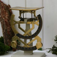 an antique brass and black clock sitting on top of a white table next to green plants