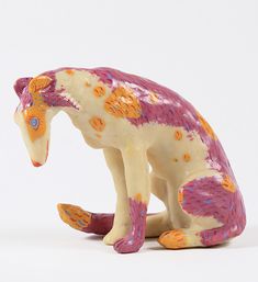 a ceramic figurine of a pink and yellow cat sitting on its hind legs