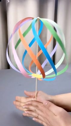 a hand holding a colorful lollipop on a stick with multicolored ribbons