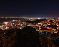 the city lights shine brightly in the night sky over a mountain top and valley below