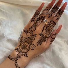 a woman's hand with henna tattoos on it and two rings in the middle