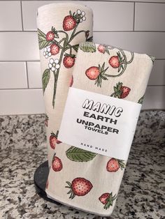 two tea towels with strawberries on them are sitting on a counter in front of a white tile wall