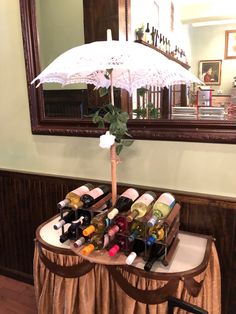a table with an umbrella and wine bottles on it in front of a mirror,