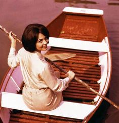 a woman sitting in a row boat on the water