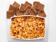 a white plate topped with crackers and a casserole dish filled with cheese