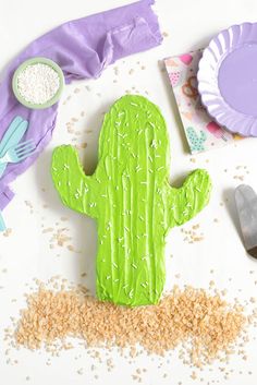 a cake shaped like a cactus sitting on top of a table next to plates and utensils
