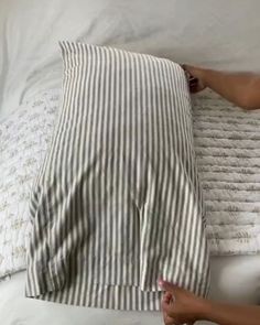 a woman laying on top of a bed next to a white and black striped pillow