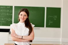 a woman standing in front of a chalkboard with her arms crossed and looking at the camera