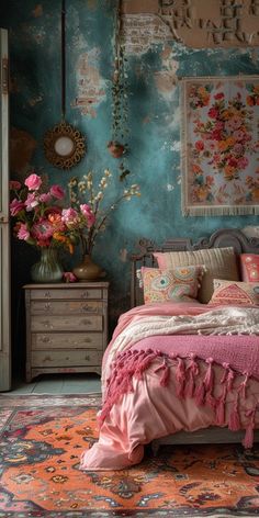 a bedroom with blue walls, pink bedding and flowers on the dresser next to it