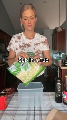 a woman standing in front of a kitchen counter holding a bag of food