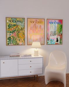 three posters hang on the wall above a white dresser with a lamp next to it