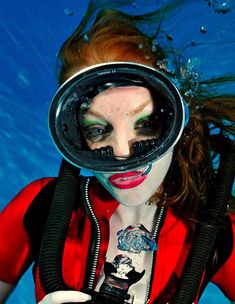 a woman wearing a diving mask and holding a camera in her hands under the water
