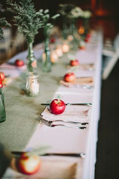 a long table with apples and candles on it