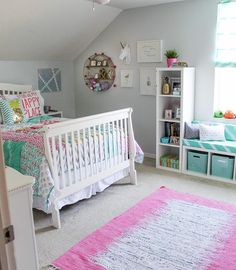 a white crib in the corner of a room with pink and blue decor on it