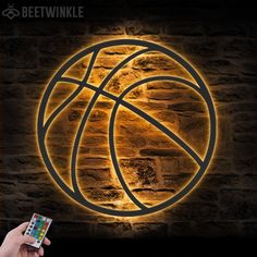 a person holding a cell phone in front of a wall with a basketball logo on it