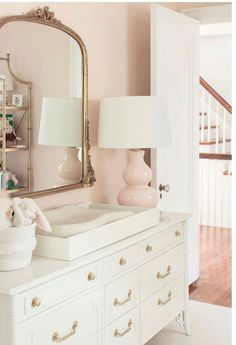 a white dresser topped with a mirror and a teddy bear sitting on top of it