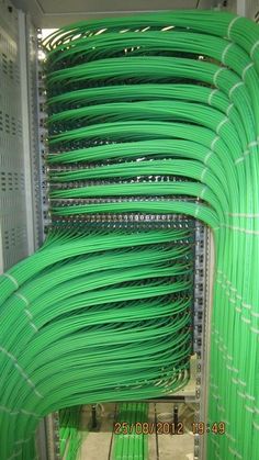 many green wires are connected to each other in a room with metal racks and shelves
