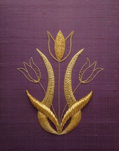 a decorative piece made out of gold leaf and flower shapes on purple fabric with metallic thread