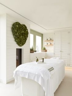 a white bed sitting in a bedroom next to a fireplace covered in greenery on top of it