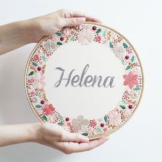 two hands holding up a embroidery kit with the word helen on it and flowers in the middle
