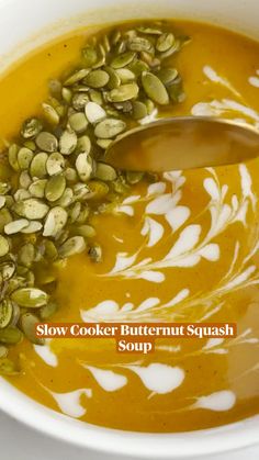 a white bowl filled with soup topped with pumpkin seeds and pistachios, next to the words slow cooker butternut squash soup