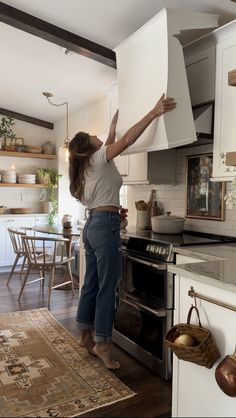 a woman reaching up into an oven in a kitchen