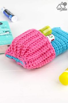 a crocheted bag sitting on top of a table next to markers and pens