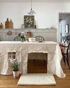 a dining room with a table and chairs covered by a white cloth covering the top