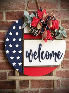 a welcome sign hanging on the side of a brick wall with red, white and blue decorations