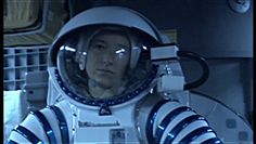 a man in an astronaut's suit holding his hand up to his face