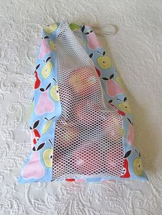 a mesh bag with apples on it sitting on a bed