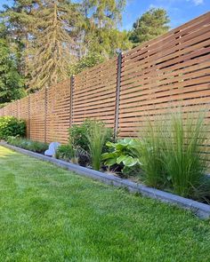 a fenced in garden area with grass and plants on the side of the fence