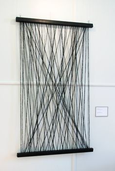 a piece of art hanging on the wall with wires attached to it's sides