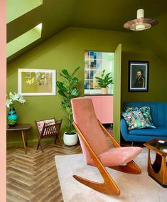 a living room with green walls and wooden furniture in the corner, including a pink rocking chair