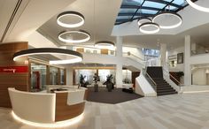an office building with several circular lights hanging from the ceiling and two staircases leading up to the second floor