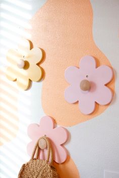 a purse hanging on the side of a wall with flowers and wooden pegs attached to it
