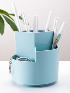 there is a blue cup that has some pens and pencils in it