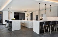 a kitchen with marble counter tops and bar stools next to an open floor plan