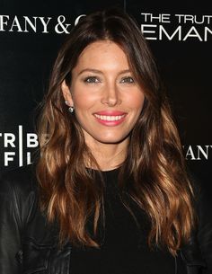 a woman with long brown hair wearing a black top and leather jacket at an event