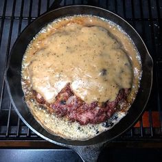 a skillet filled with meat and gravy sitting on top of a stove